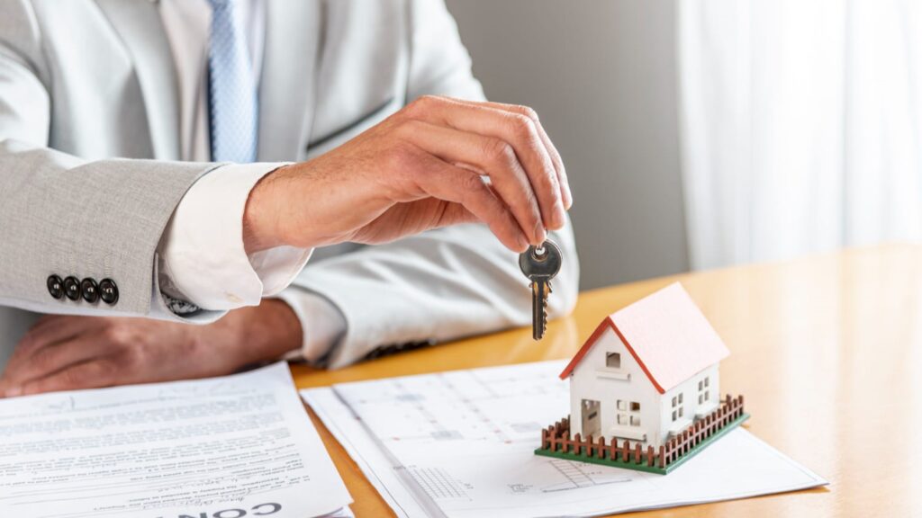 Makelaars overhandigen huissleutels bij contractbespreking, symbool voor vertrouwen in makelaars